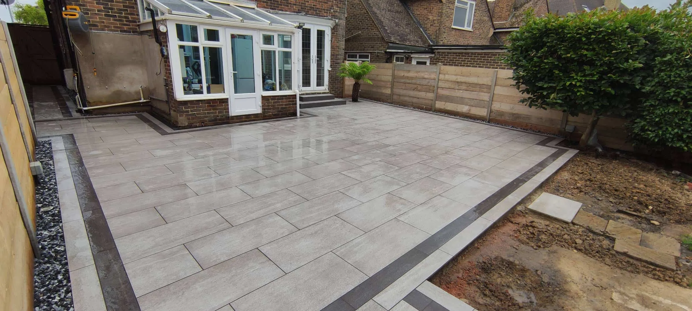 Large Italian porcelain patio with contrasting plank border in Bexhill