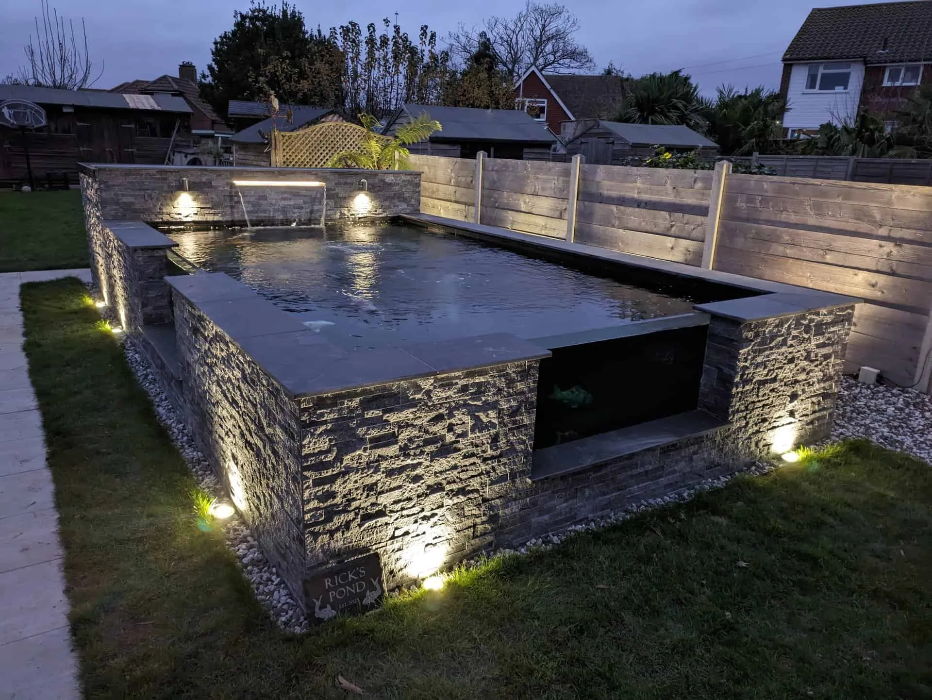 Koi pond with slate coping lit at dusk in Bexhill
