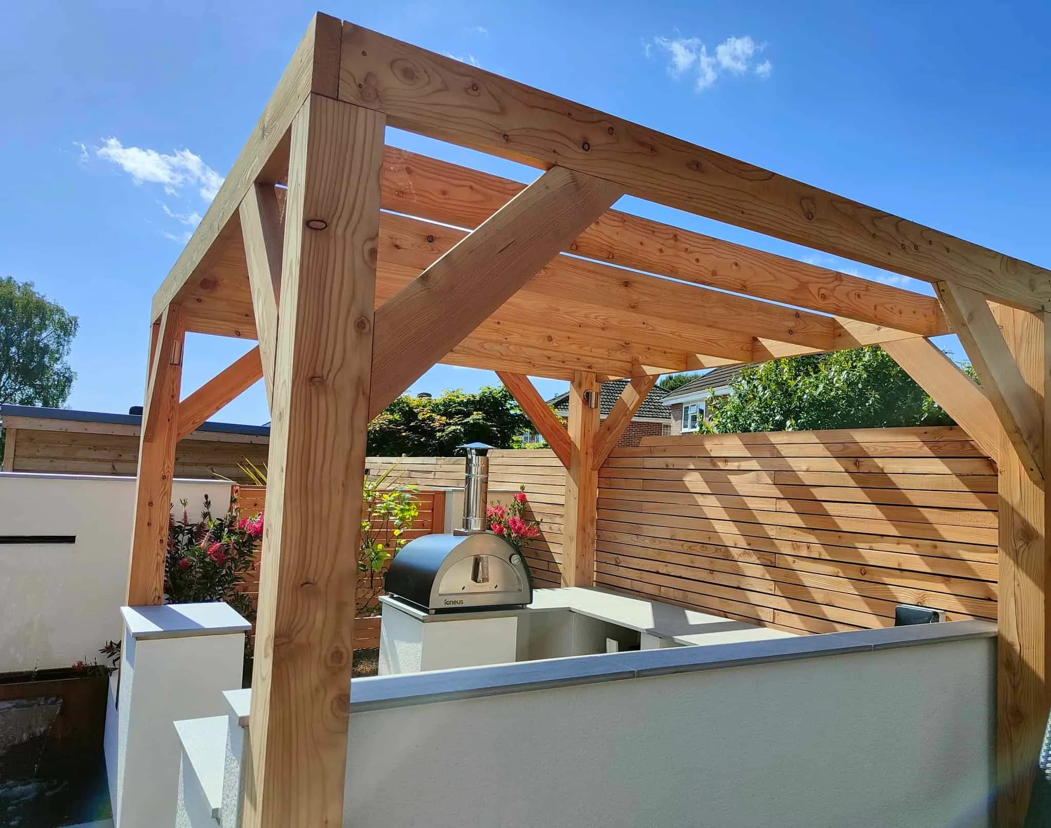 Larch pergola over an outdoor kitchen in a modern Hailsham garden